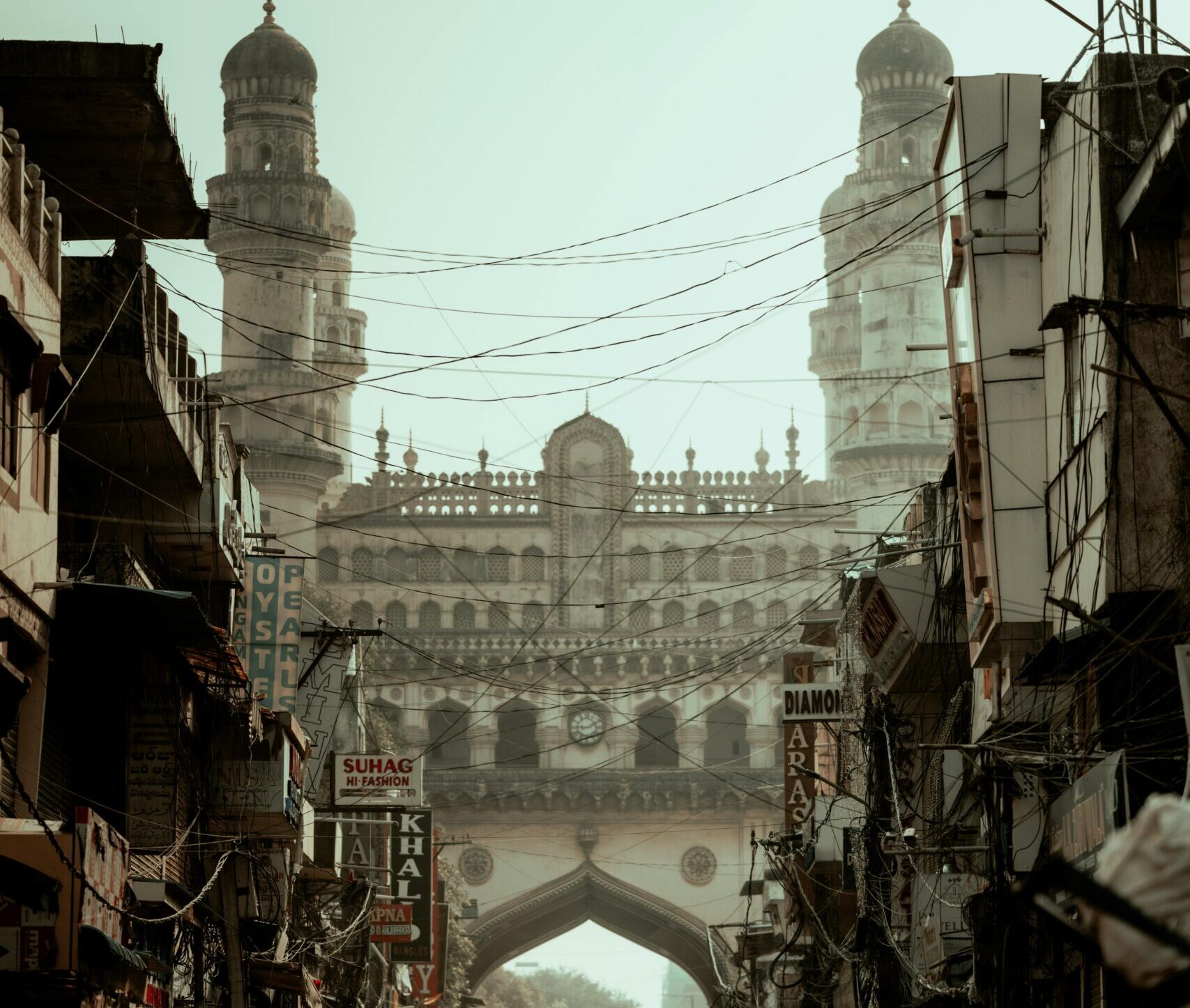 Vertical shot of Charminar, Hyderabad's iconic monument, amidst bustling street scene.